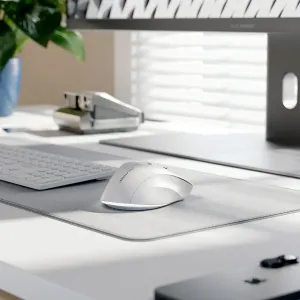 Alogic APEX valge ergonoomiline juhtmevaba hiir lauamatil, näidatud koos klaviatuuriga moodsas töökeskkonnas.