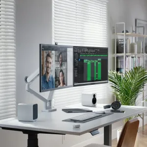 Weißer Alogic Glide Dual-Monitorarm, auf einem Schreibtisch montiert, mit zwei Monitoren in einem ergonomischen Arbeitsbereich