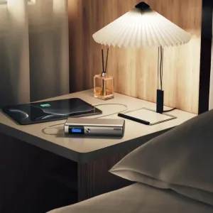 ALOGIC 20,000mAh power bank with digital display charging on a bedside table in a bedroom