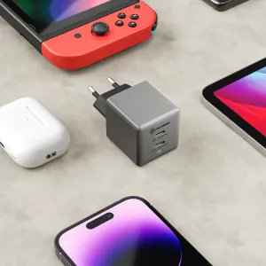 ALOGIC dubbel USB-C-laddare på 45 W i kubformat med två portar, visad bredvid telefon, surfplatta och öronsnäckor på ett skrivbord.