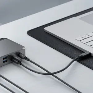 ALOGIC PRIME DX2 Universal Dock ansluten till en bärbar dator med kablar på ett skrivbord, en kompakt grå arbetsstationshubb.
