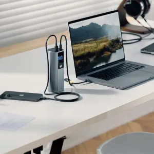 ALOGIC Ark Pro-powerbank laddar en bärbar dator och en smarttelefon på ett skrivbord, med en inbyggd skärm och anslutna kablar.