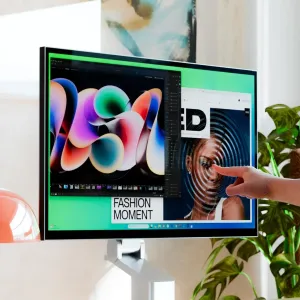 Alogic Clarity 32-Zoll-6K-Touchscreen-Monitor auf Ständer, mit einer Hand, die das farbenfrohe Desktop-Display berührt