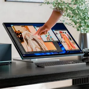 ALOGIC 32-Zoll-Touchscreen-Monitor auf einem Klappständer mit einer Hand, die Touch-Bedienelemente auf einem Schreibtisch nutzt.