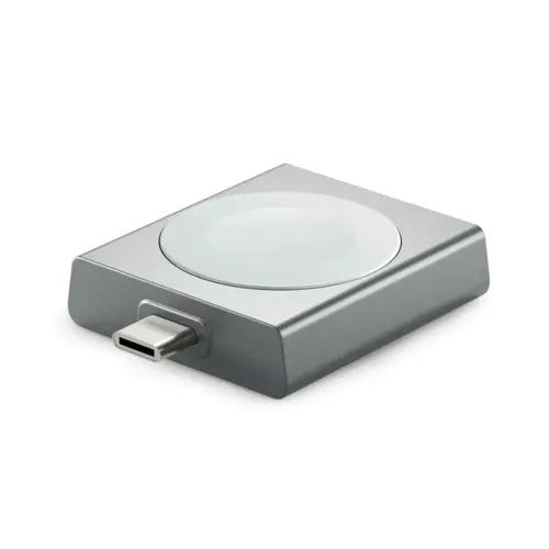 Rektangulär Apple Watch-laddare i metallgrått med rund laddningsplatta och USB‑C-hane på kortsidan, visad snett i närbild.