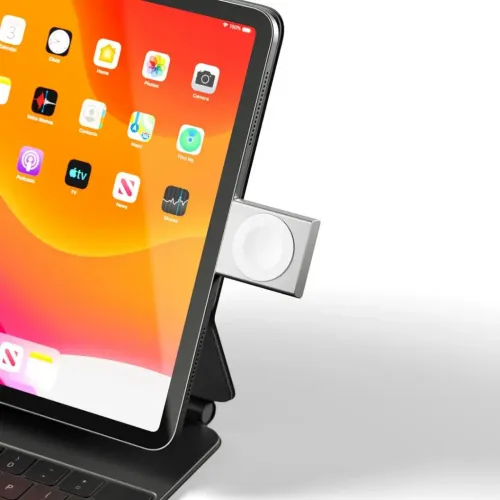 Apple Watch-laddare med USB‑C, kompakt fyrkantig modul ansluten i surfplattans sidport med vit magnetisk laddskiva i silver.