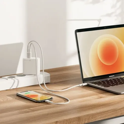 ALOGIC 63W GaN USB-C-lader med to porter i grenboks, to USB-C-kabler lader en bærbar datamaskin og en telefon på skrivebordet.