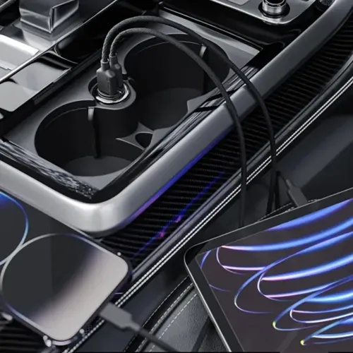 Auton pikalaturi, jossa on kaksi porttia 12 V:n pistorasiassa, kaapelit kytketty, keskikonsolissa kupinpidikkeen vieressä, matkapuhelin ja tabletti.