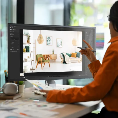 Juodos spalvos rašiklis, laikomas rankoje priešais kompiuterio ekraną, kuriame redaguojamas vaizdas; siauras cilindro formos korpusas su matomu antgaliu ir šoniniu mygtuku.
