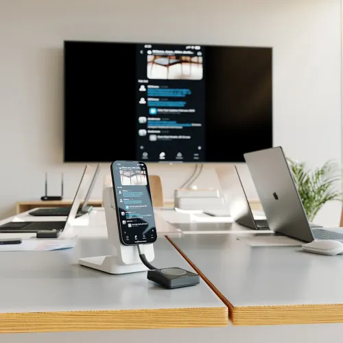 ALOGIC Unite 4K presentatörsknapp med kort USB-C-svans på konferensbord, ansluten till telefon på ställ; stor skärm speglar.