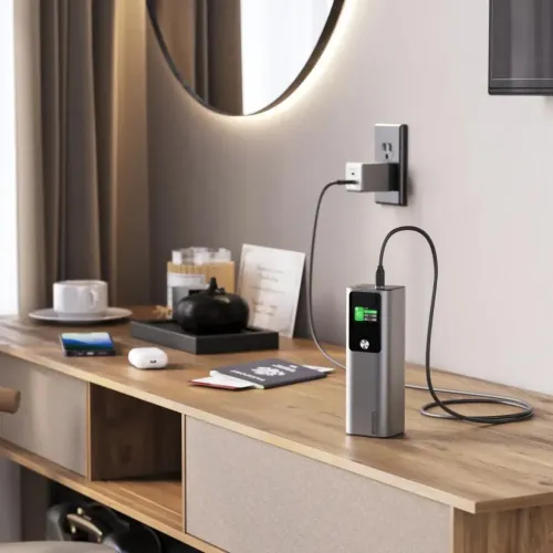 Alogic Ark sølvfarget powerbank med digital skjerm, stående med USB-C-kabel tilkoblet på et trebord