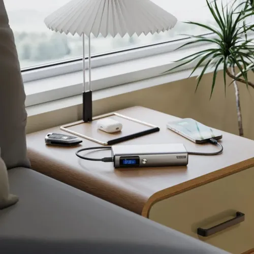 ALOGIC Ruck powerbank i silver, rektangulär med blå display och sidoknapp, USB‑C‑kabel till telefon, på bord vid fönster