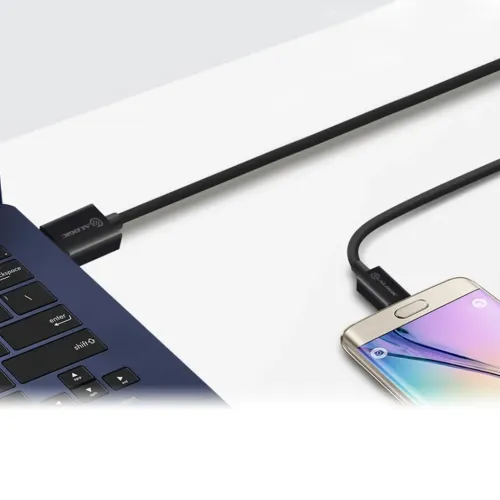 Reversibel USB-A till Micro-USB-kabel inkopplad mellan en bärbar dators USB-port till vänster och en smartphone till höger.