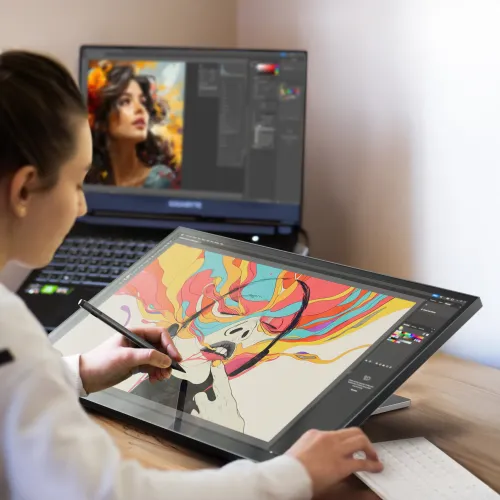 ALOGIC Clarity 27" berøringsskjerm på vippbart stativ, brukt med penn på skrivebordet ved siden av bærbar PC og tastatur.
