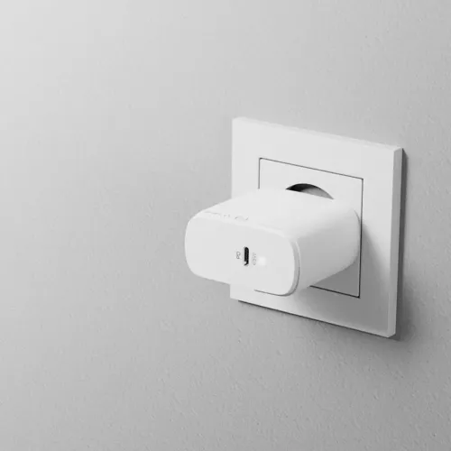 Vit väggladdare med rundade kanter, ansluten i vägguttag, sedd i sidoprofil med en USB‑C‑port märkt PD 65W och indikator.