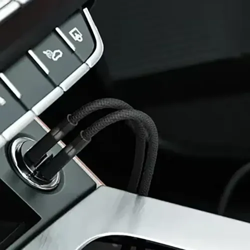 Compact space gray car charger with two USB-C ports in the car cigarette socket, two braided cables connected, shown in close-up.