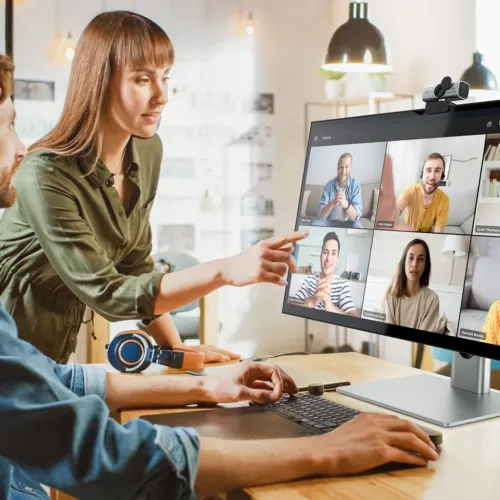 ALOGIC Clarity 27-inch UHD 4K monitor on a silver stand, showing a video conference call with webcam