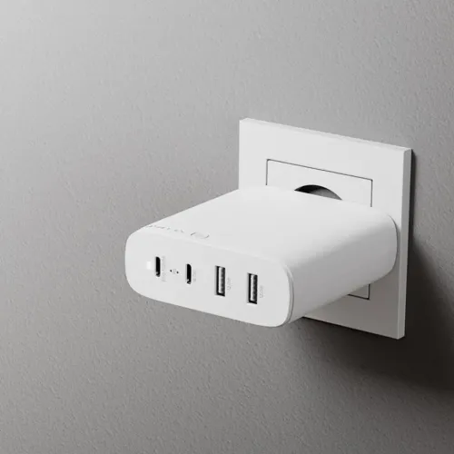 Vit väggladdare i vägguttag, med rundade kanter och front med USB‑C- och USB‑A‑portar; profil som sticker ut från väggen.