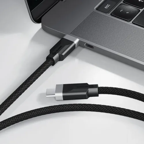 ALOGIC Fusion USB-C til USB-C-kabel med flettet sort kappe, det ene stik i den bærbare computers USB-C-port, det andet på bordet.