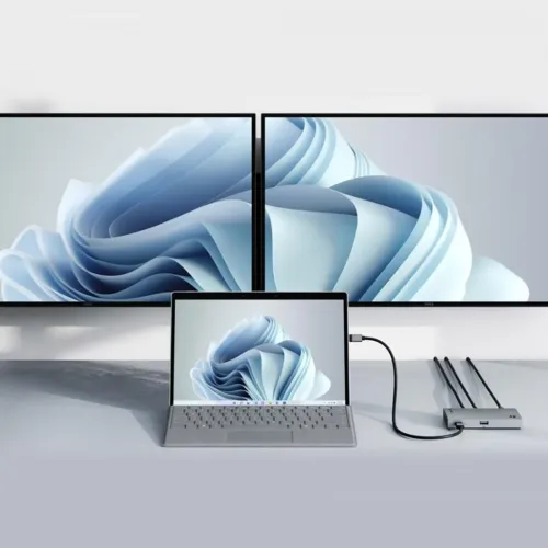 Thunderbolt 4-hub i aluminium med USB-A-port foran og tre kabler bagpå, tilsluttet en bærbar computer, der driver to store skærme.