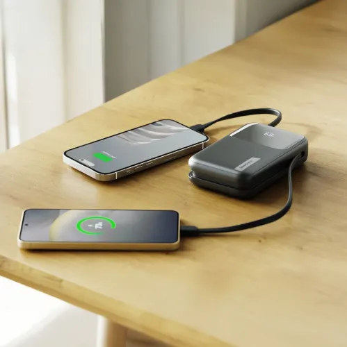 ALOGIC Tandem+ powerbank laddar två smarttelefoner med inbyggda kablar på ett träbord