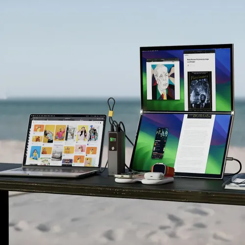 Ark Pro powerbank i silver står upprätt på bord med liten display, clip-on USB‑C-kabel och portar upptill bredvid laptop.