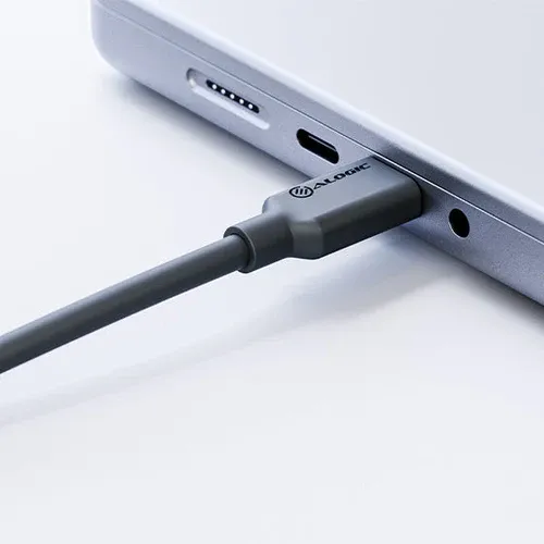 ALOGIC USB-C kabelis, prijungtas prie nešiojamojo kompiuterio USB-C prievado; pilkas kištukas su logotipu, šalia ausinių lizdo ir papildomo prievado šone.