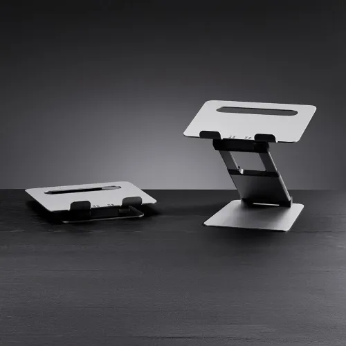 Justerbart silverfärgat laptopstativ i aluminium, ett hopfällt till vänster och ett upphöjt Z-ledat till höger med kuddar.