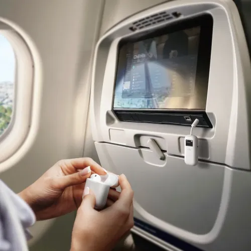 ALOGIC SkySound hvid Bluetooth-lydsender med display og knapper, forbundet med kort 3,5 mm kabel til flyets display.