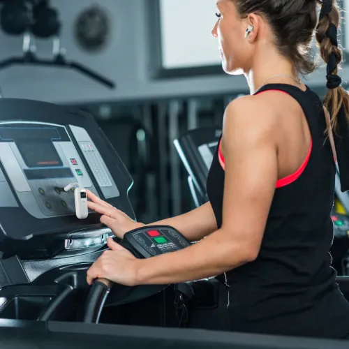 ALOGIC SkySound hvid Bluetooth-lydsender med 3,5 mm-stik er fastgjort til løbebåndets panel ved knapperne og displayet.