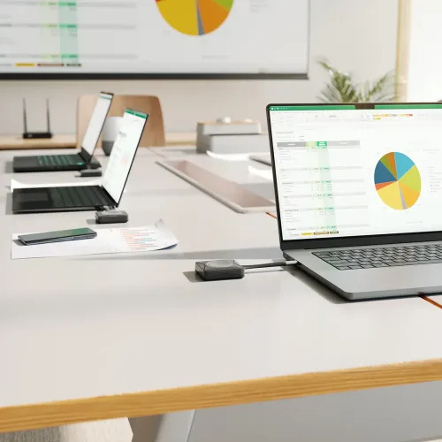 USB‑C presentatörsknapp för trådlös delning ansluten till laptop på mötesbord, laptops med knappar och projicerad skärm.